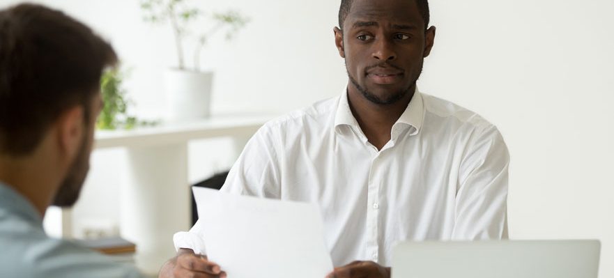 Entrevistador preguntando a un candidato por qué quiere dejar su trabajo