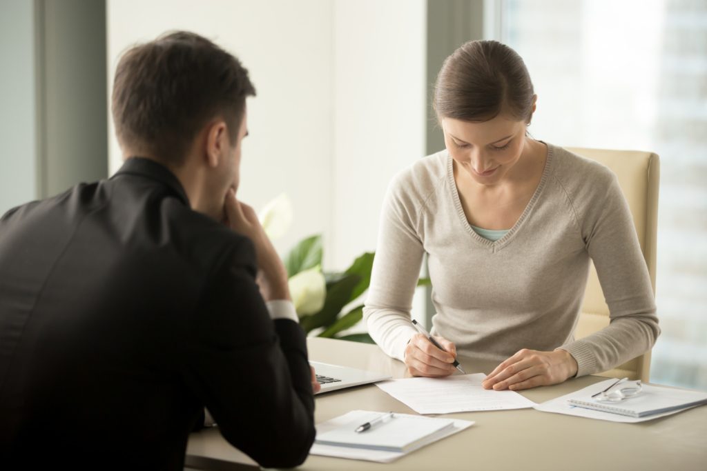 Joven firmando un contrato con periodo de prueba en empleo