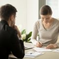 Joven firmando un contrato con periodo de prueba en empleo