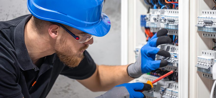 Electricista trabajando en un cuadro eléctrico con un cable de conexión. Magnific